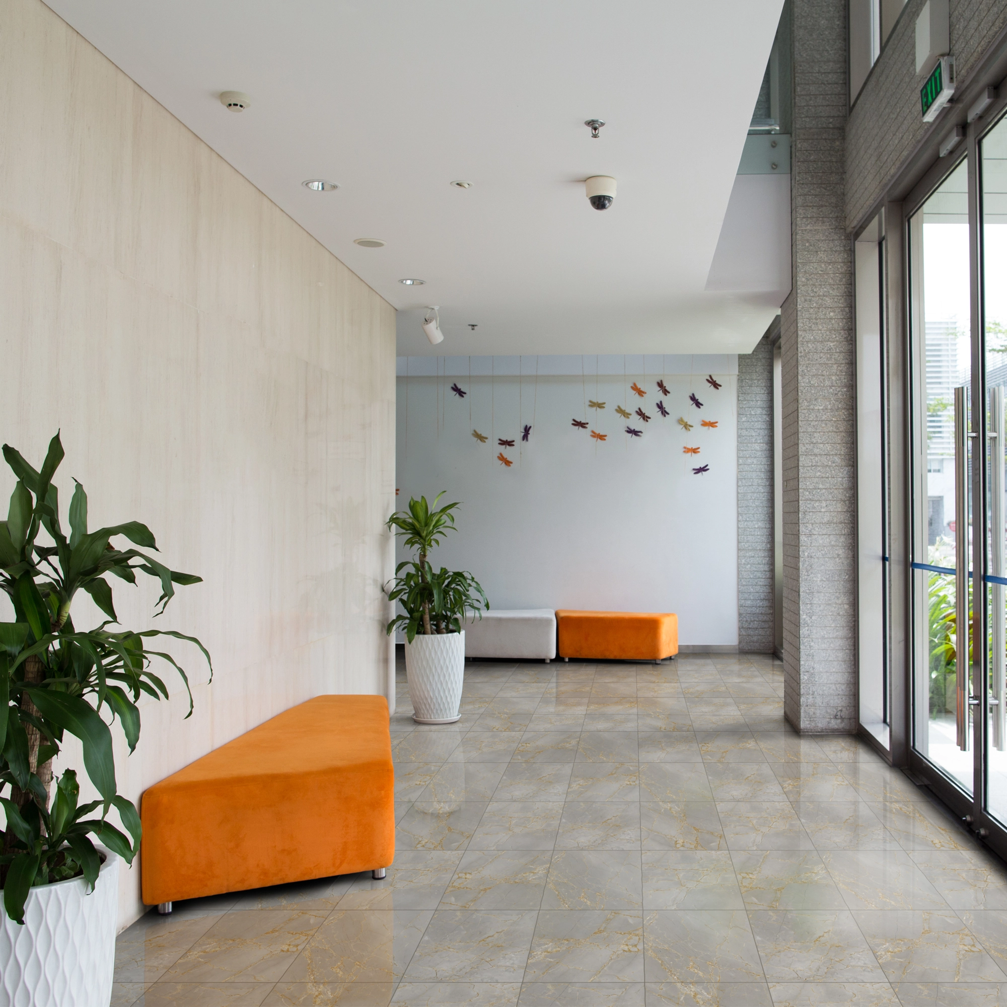 Recepción con iluminación natural, asientos de espera naranja y piso de cerámica mármol Dorato, colección Ecos de Cerámicos Gala